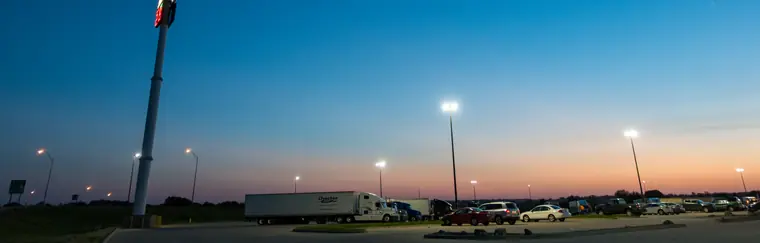 A truck stop in Minnesota at dusk: parking-lot lights on, a tractor-trailer parked at the left of the lot